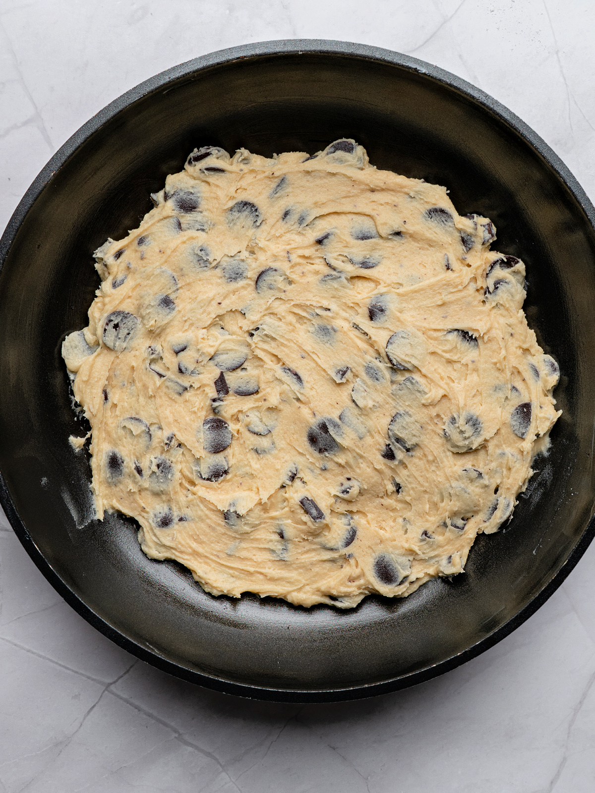Chocolate chip cookie dough in the bottom of a skillet.