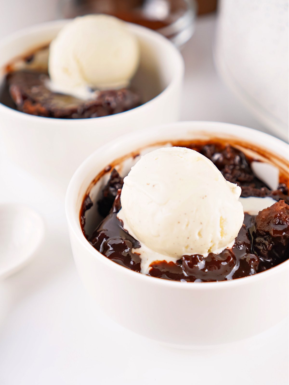 Two bowls of freshly Crockpot-baked chocolate cobbler topped with vanilla ice cream.