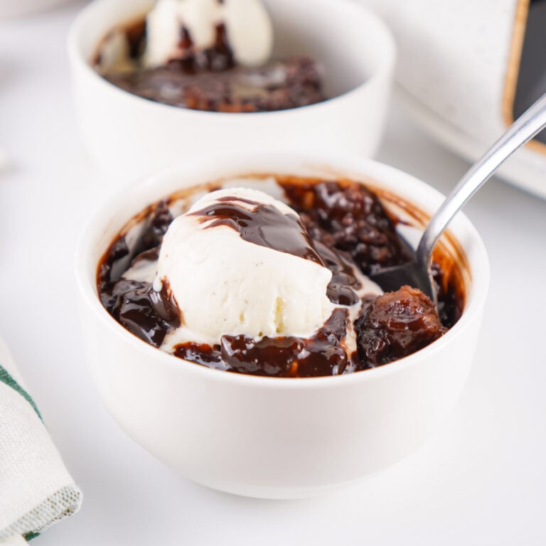 A bowl of chocolate cobbler topped with a scoop of vanilla ice cream.