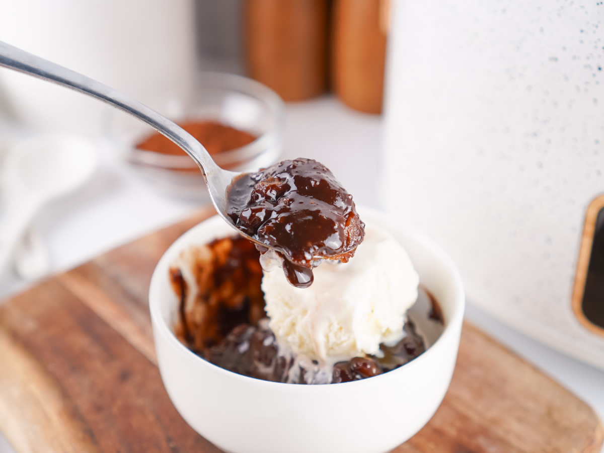 Spoonful of warm chocolate cobbler topped with melting vanilla ice cream.