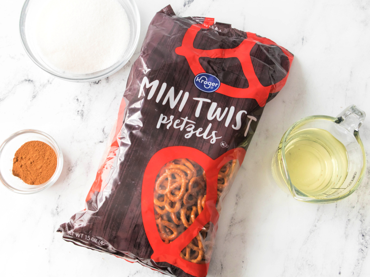 Ingredients laid out to make cinnamon sugar pretzels, including pretzels, sugar, cinnamon, and oil.