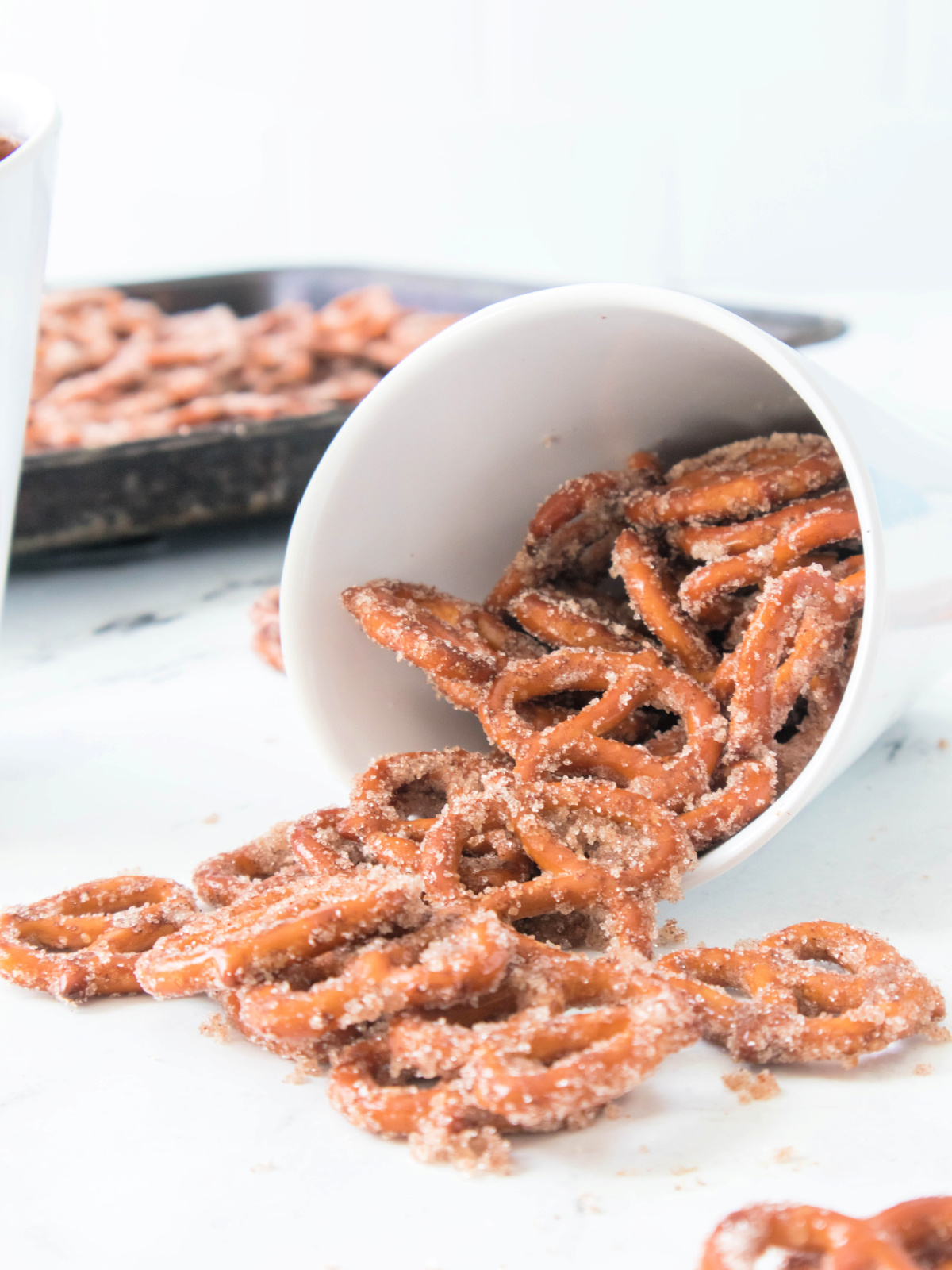 Cinnamon sugar pretzels spilling out of a white bowl after baking.
