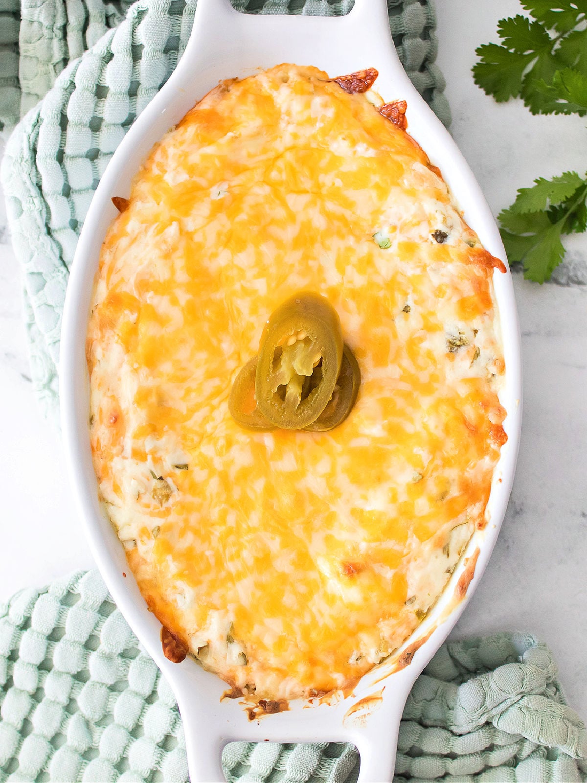 Golden baked jalapeño cream cheese dip garnished with sliced jalapeños on top.