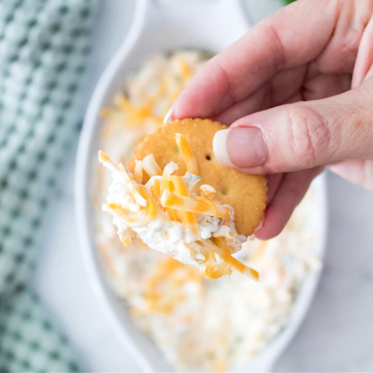 A view of a Ritz cracker with jalapeño cream cheese dip held in hand.