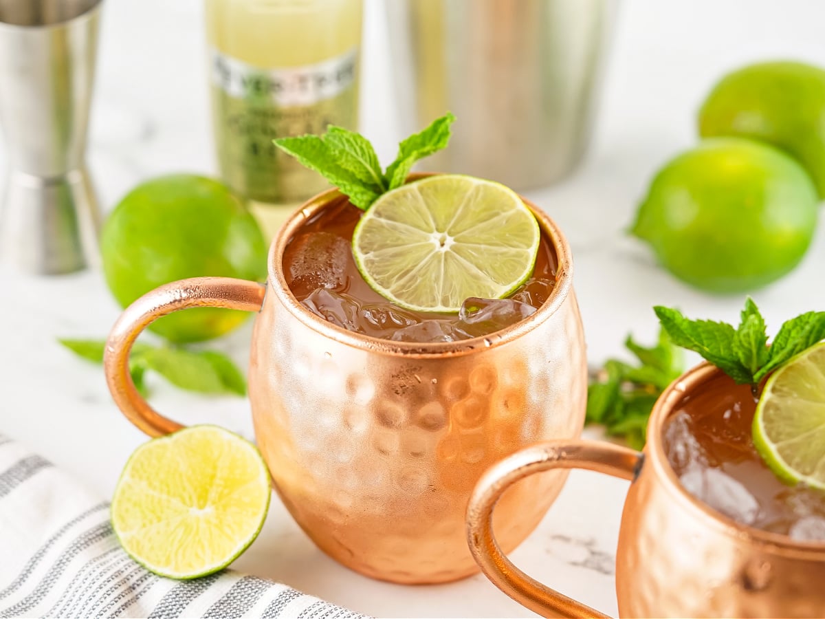 Two frosty copper mugs filled with Moscow Mules, garnished with lime wedges.