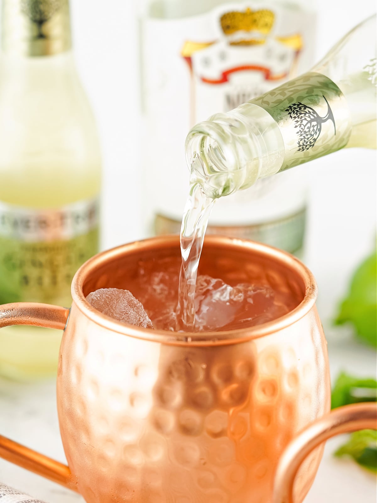 Vodka being poured into a copper mug to make a Moscow Mule cocktail.
