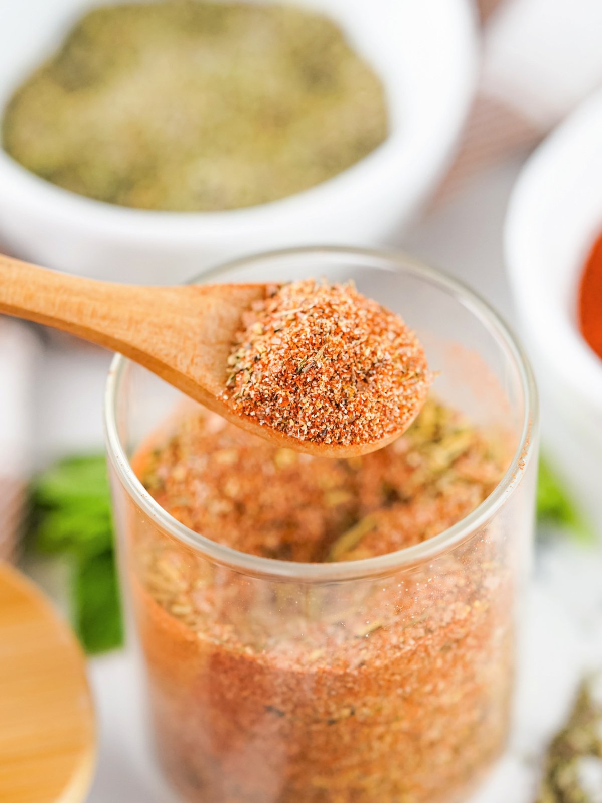 A wooden spoon filled with homemade turkey rub showcasing paprika and herbs.