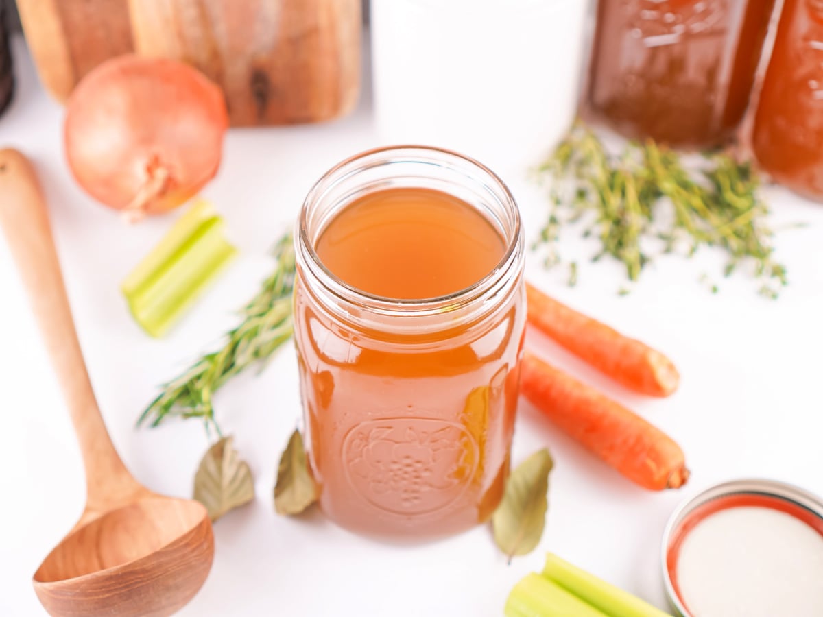 A jar of freshly made vegetable stock sitting on a kitchen counter.