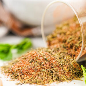 Close-up of homemade turkey rub spilling from a jar, showing texture and color.