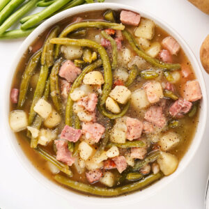 A bowl of ham, green beans, and potatoes, highlighting the rustic Southern comfort meal.