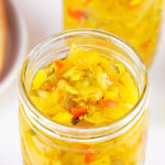 Homemade sweet pickle relish in a glass jar with chopped cucumbers and peppers in brine.