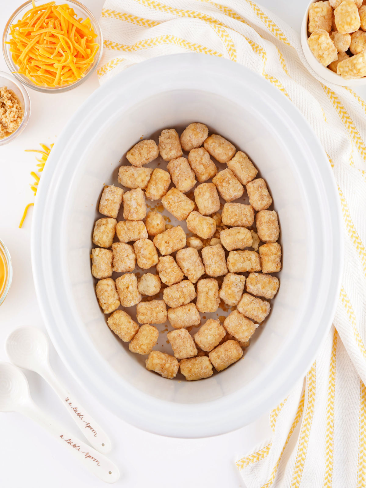 Frozen tater tots arranged in a single layer at the bottom of a crockpot.