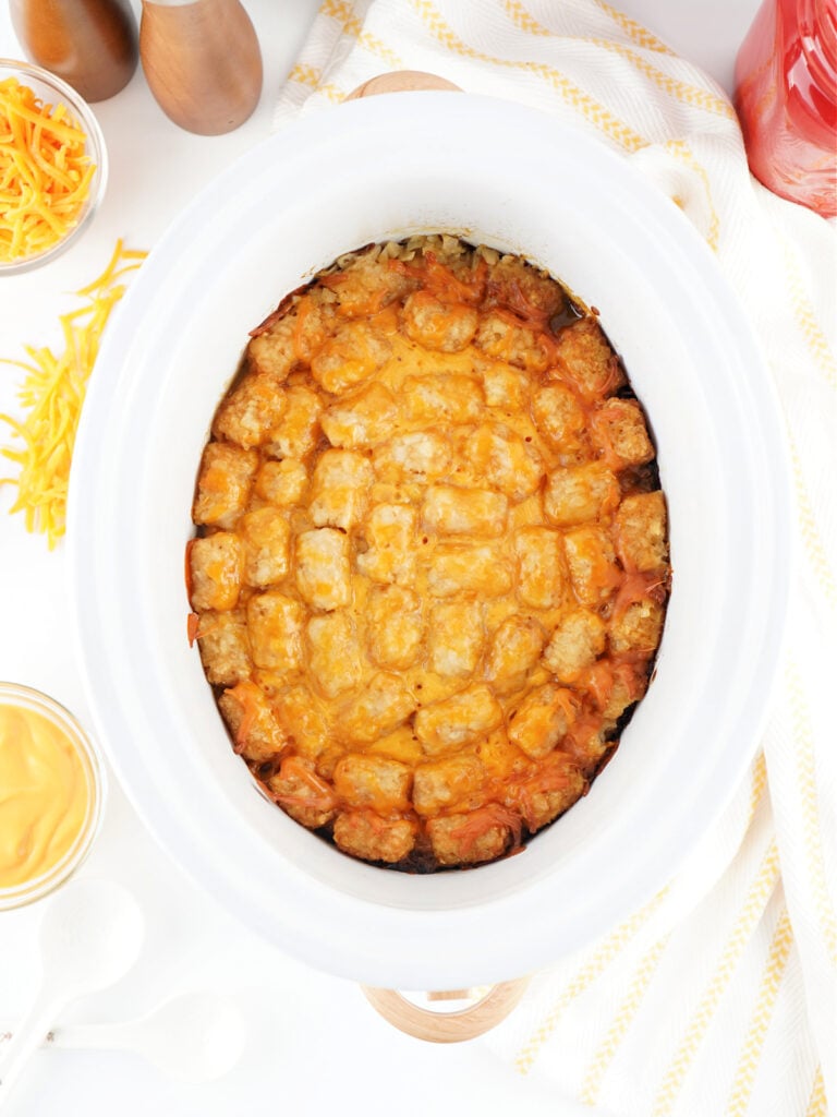Fully cooked crockpot taco tater tot casserole with melted cheese and golden tater tots.