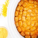 Crockpot taco tater tot casserole with melted cheese and seasoned ground beef.