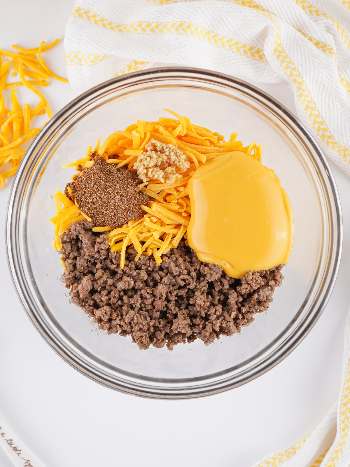 Cooked ground beef in a bowl with cheeses and spices.