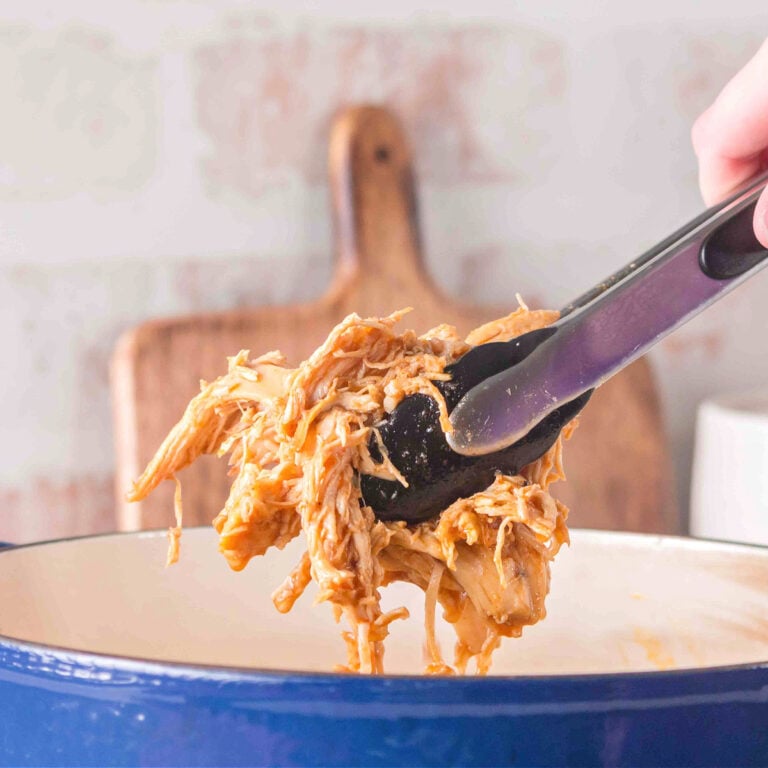 Dutch oven filled with juicy shredded BBQ chicken coated in homemade sauce.