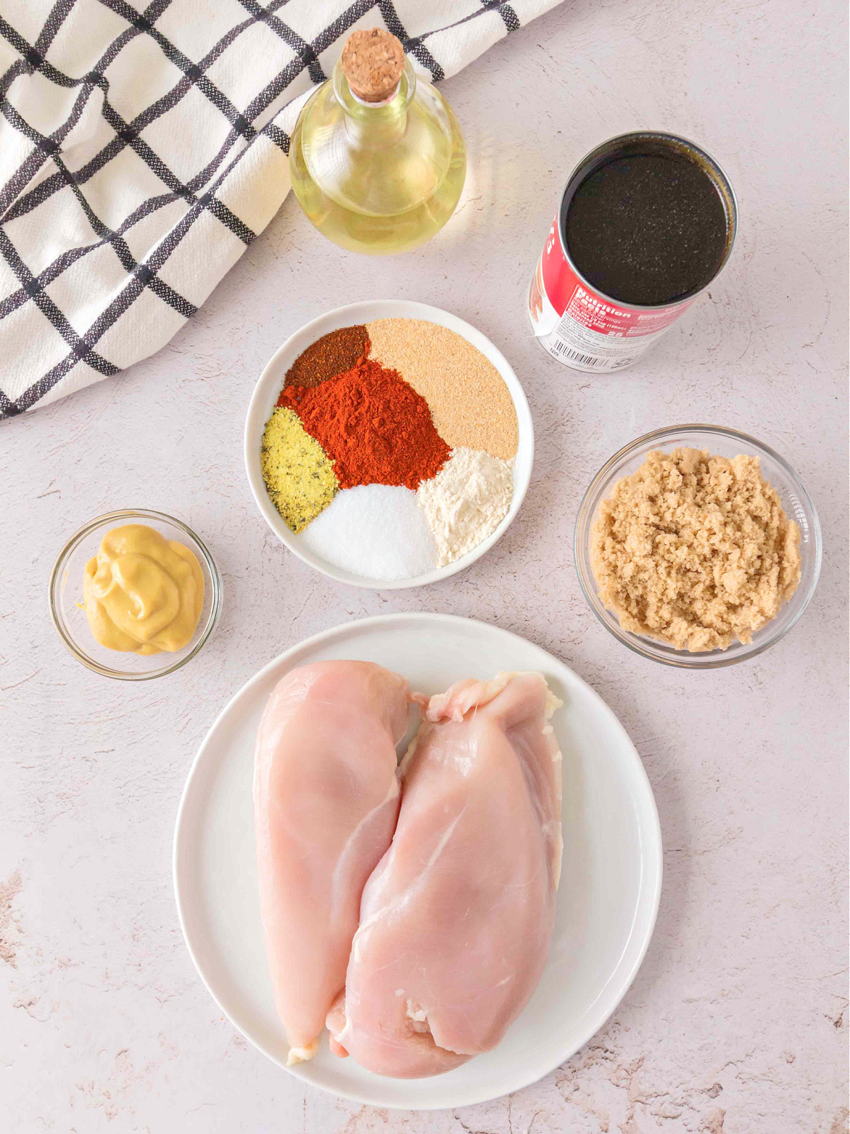 Raw chicken breasts with BBQ seasoning ingredients including brown sugar, spices, mustard, oil, and beef consommé.
