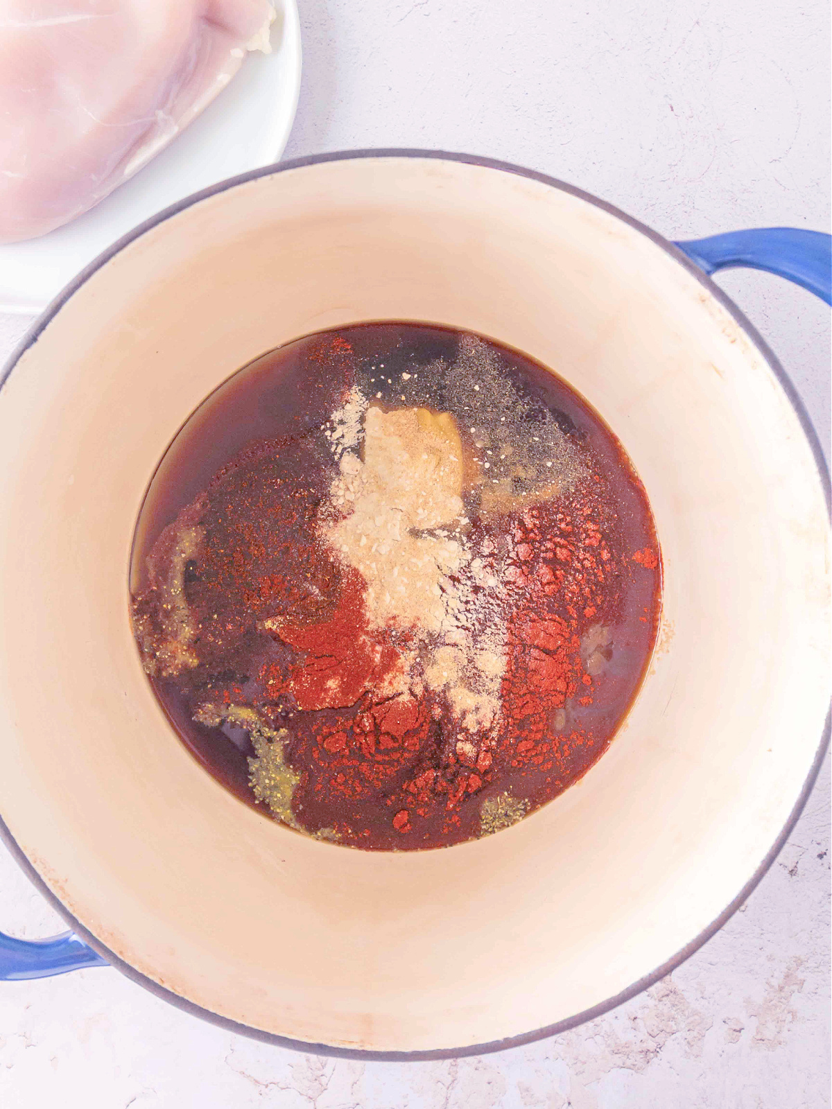 BBQ sauce ingredients and spices added to liquid in a Dutch oven before cooking.