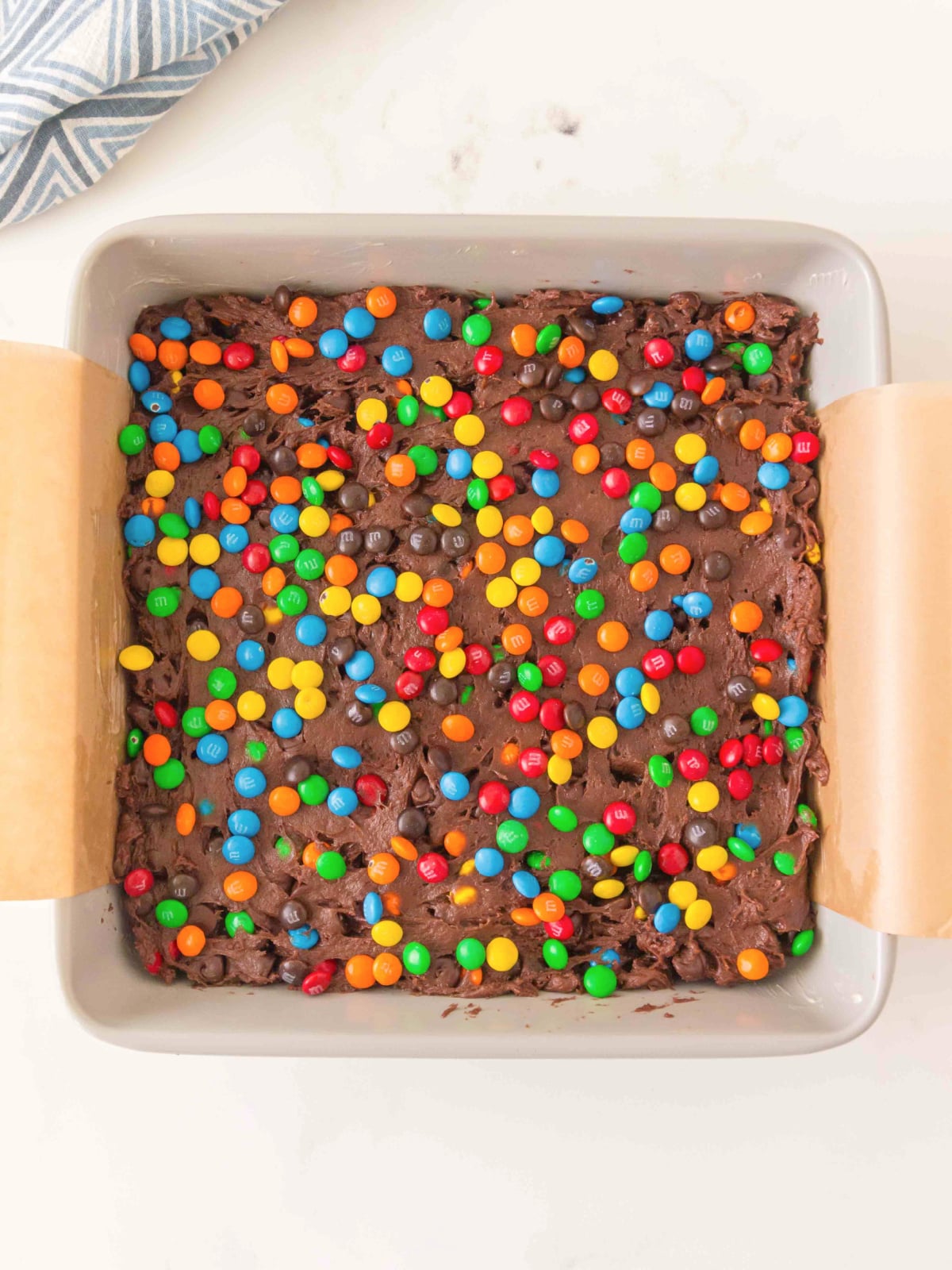 Unbaked brownie batter spread in a baking dish and topped with M&M candies before baking.