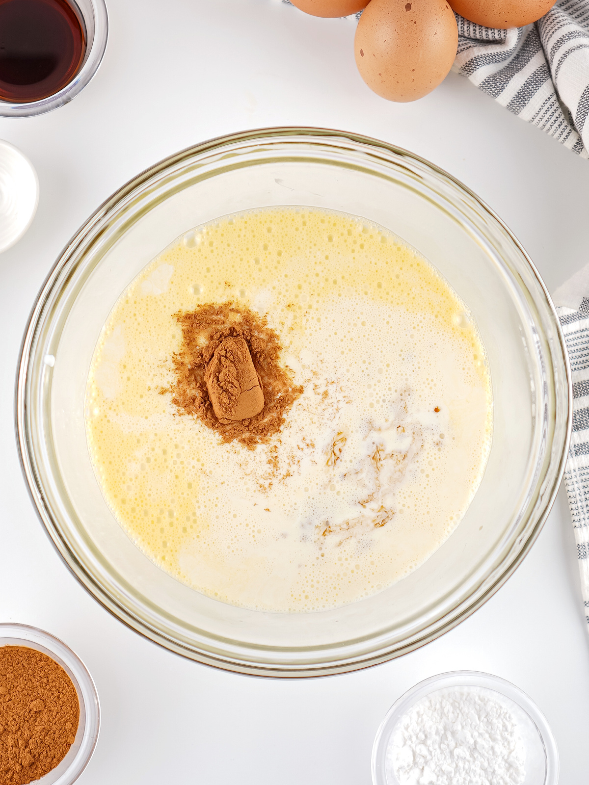 Bread pudding custard made with milk, eggs, cinnamon, and vanilla in a glass bowl.