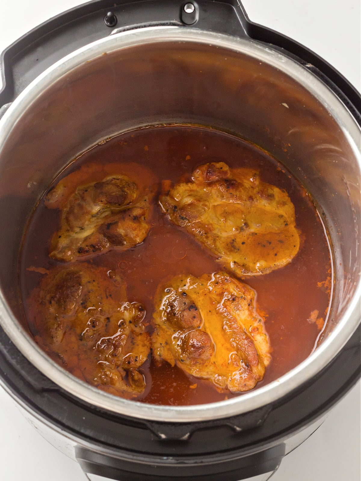 Pork cooking in broth inside an instant pot after pressure cooking.