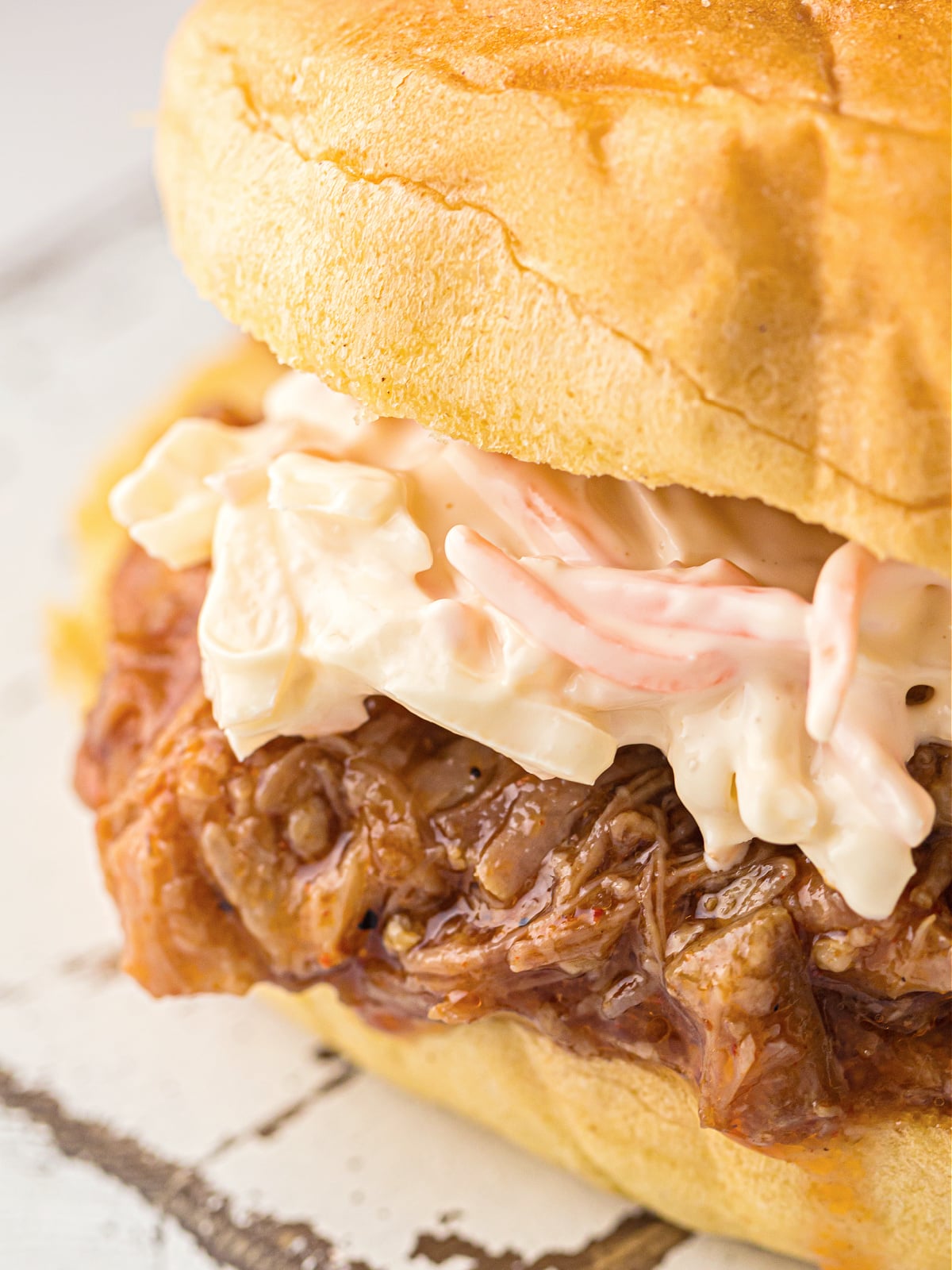 Instant pot pulled pork sandwich topped with creamy coleslaw on a soft bun.