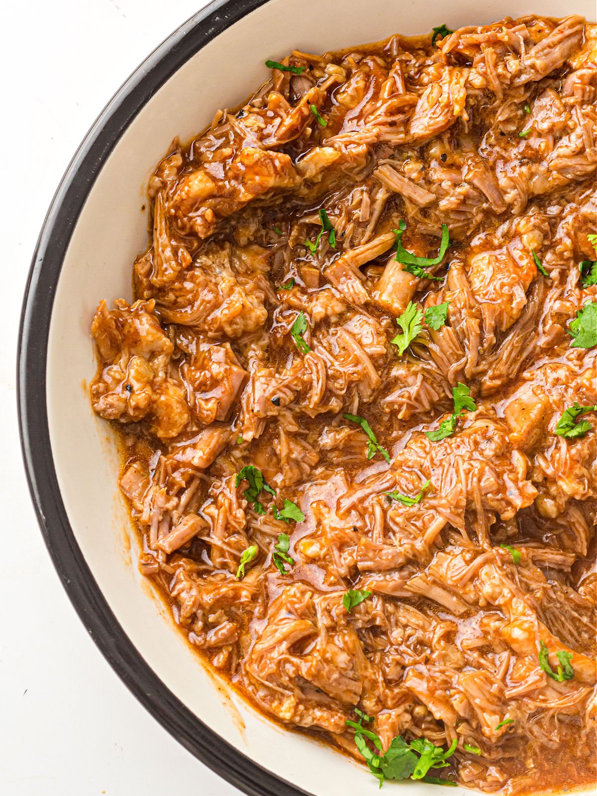 Shredded instant pot pulled pork mixed with barbecue-style sauce.