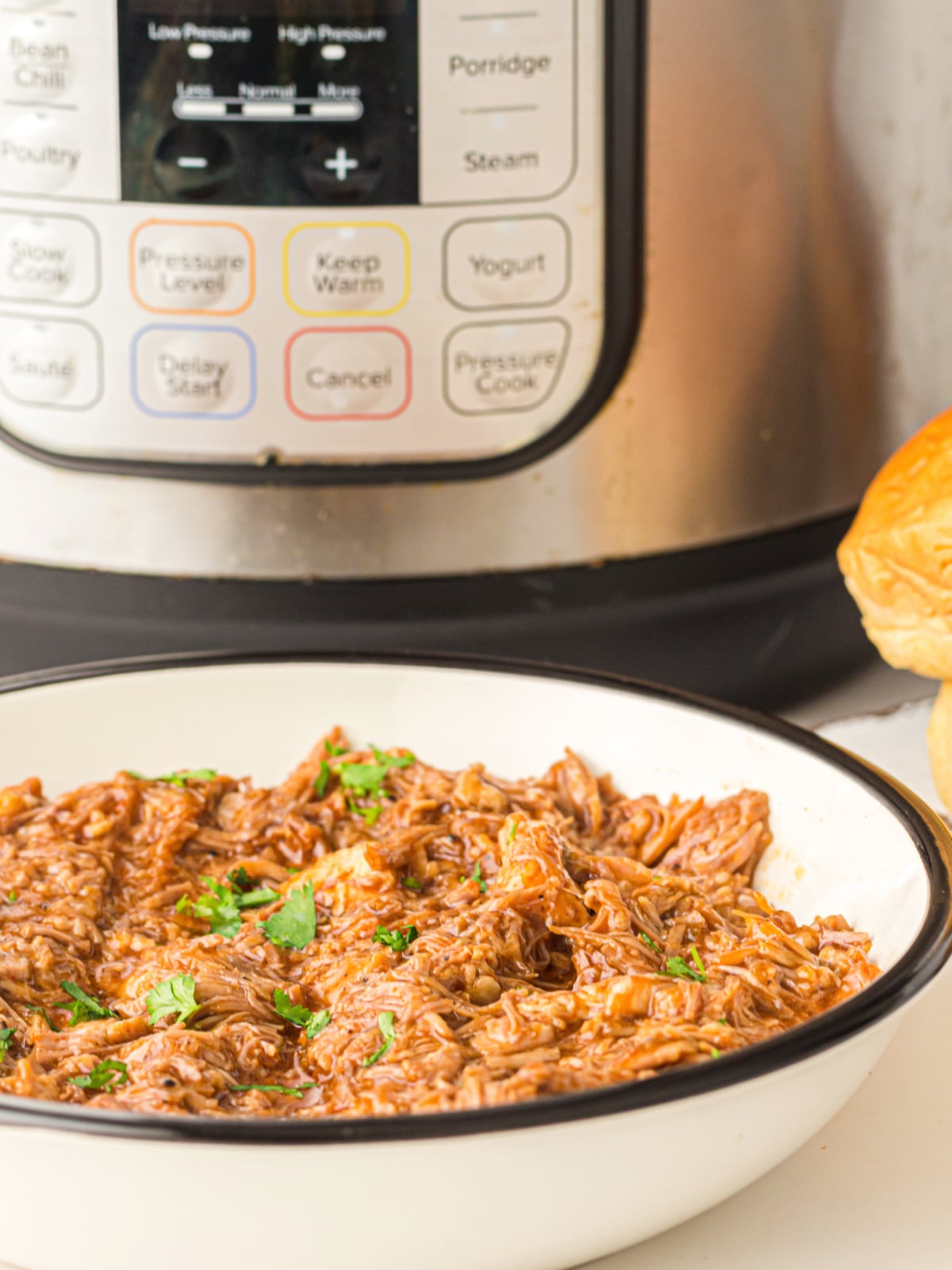 Instant pot pulled pork ready to serve in a white enamel bowl.