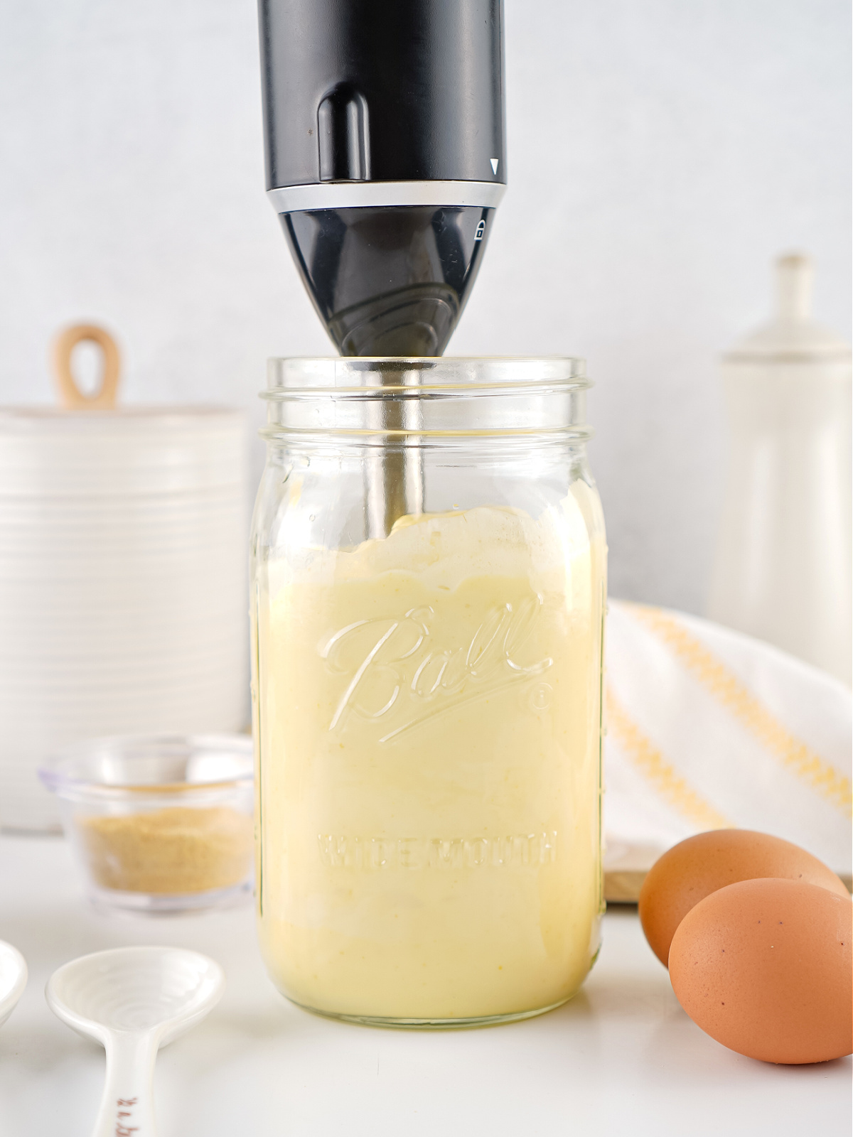 Immersion blender emulsifying homemade mayonnaise inside a wide-mouth mason jar.