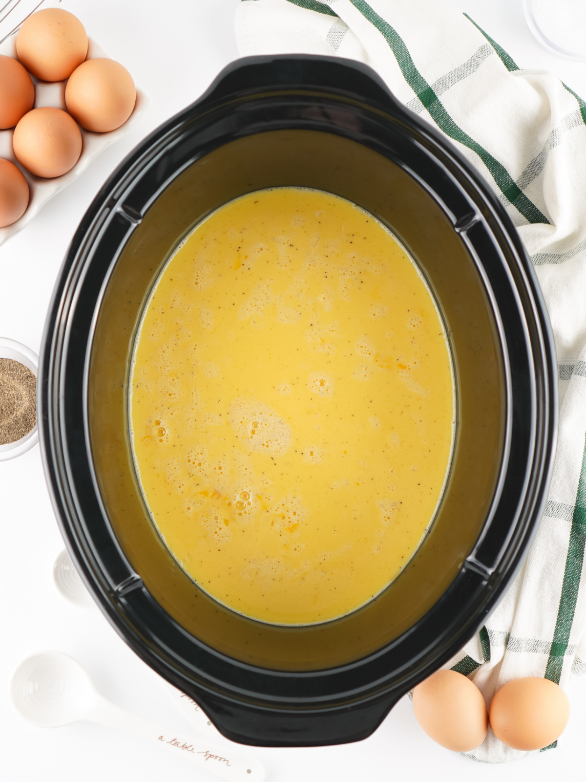 Whisked eggs and milk mixture in the bottom of the crock of a Crockpot.