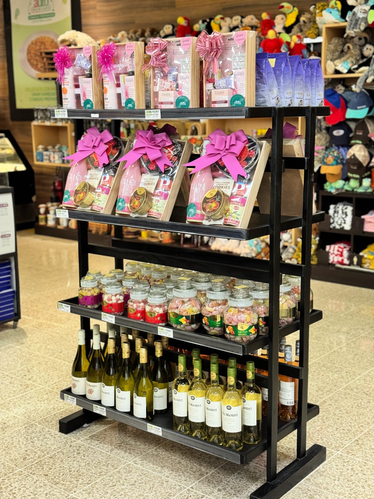 Gift baskets, jars of candy, and wine bottles displayed on a shelf inside Auto Mercado in Costa Rica.
