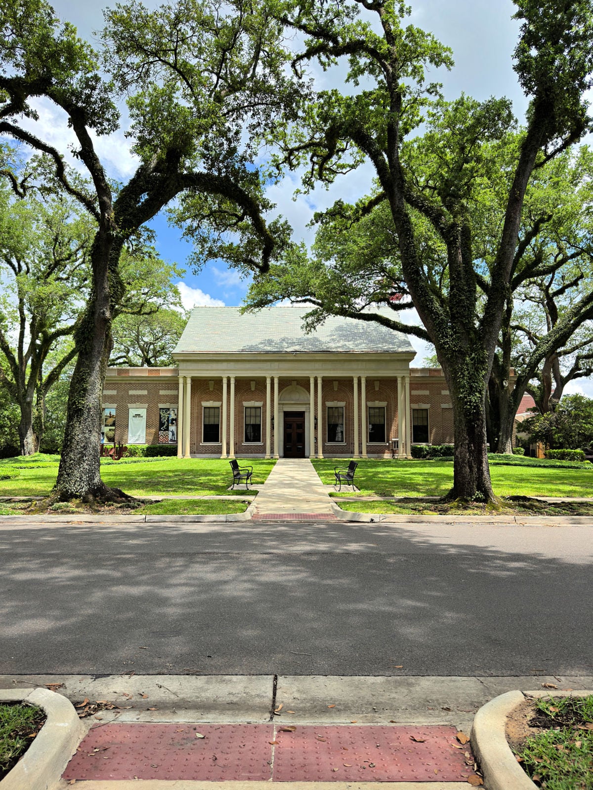 Lauren Rogers Museum of Art building framed by oak trees and benches along the front walkway in Laurel.
