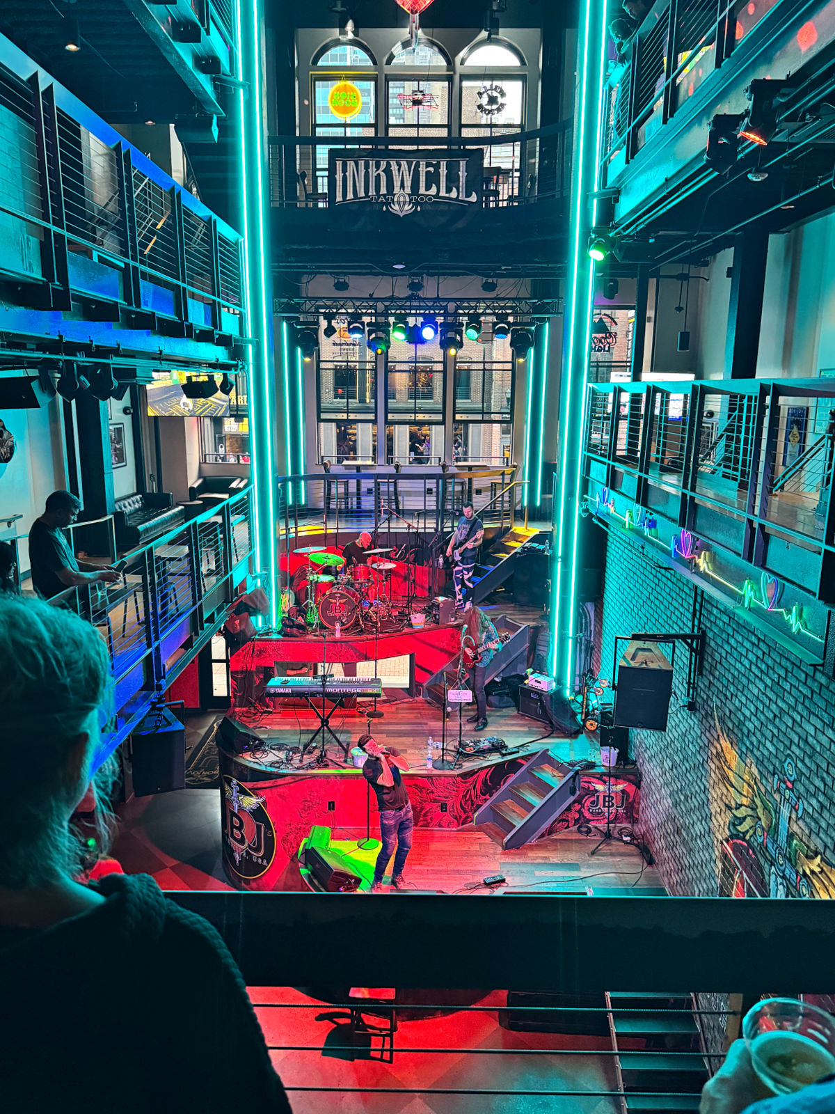 Interior view of a multi-level live music venue on Broadway with a band performing under colorful stage lights.
