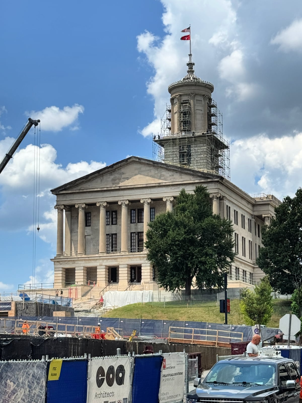 The Tennessee State Capitol building in Nashville with scaffolding during restoration and an American flag flying above.