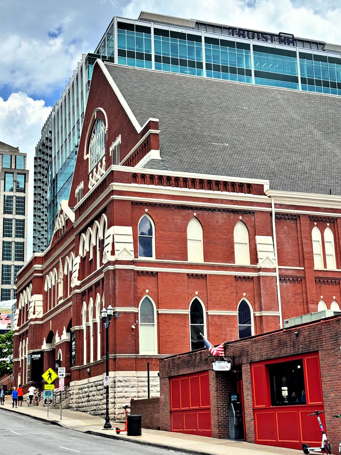 Exterior view of the historic Ryman Auditorium in downtown Nashville with surrounding city buildings.