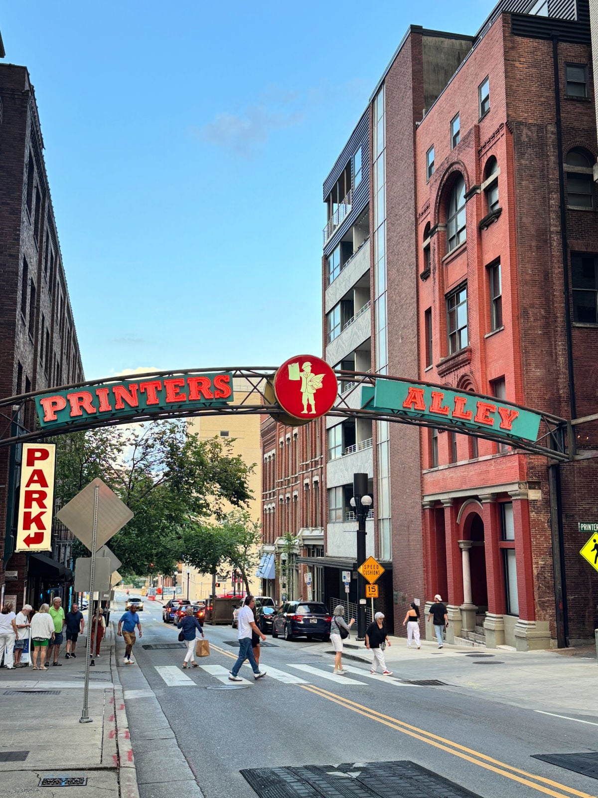 Printers Alley entrance sign spanning a historic downtown Nashville street with brick buildings and pedestrians below.