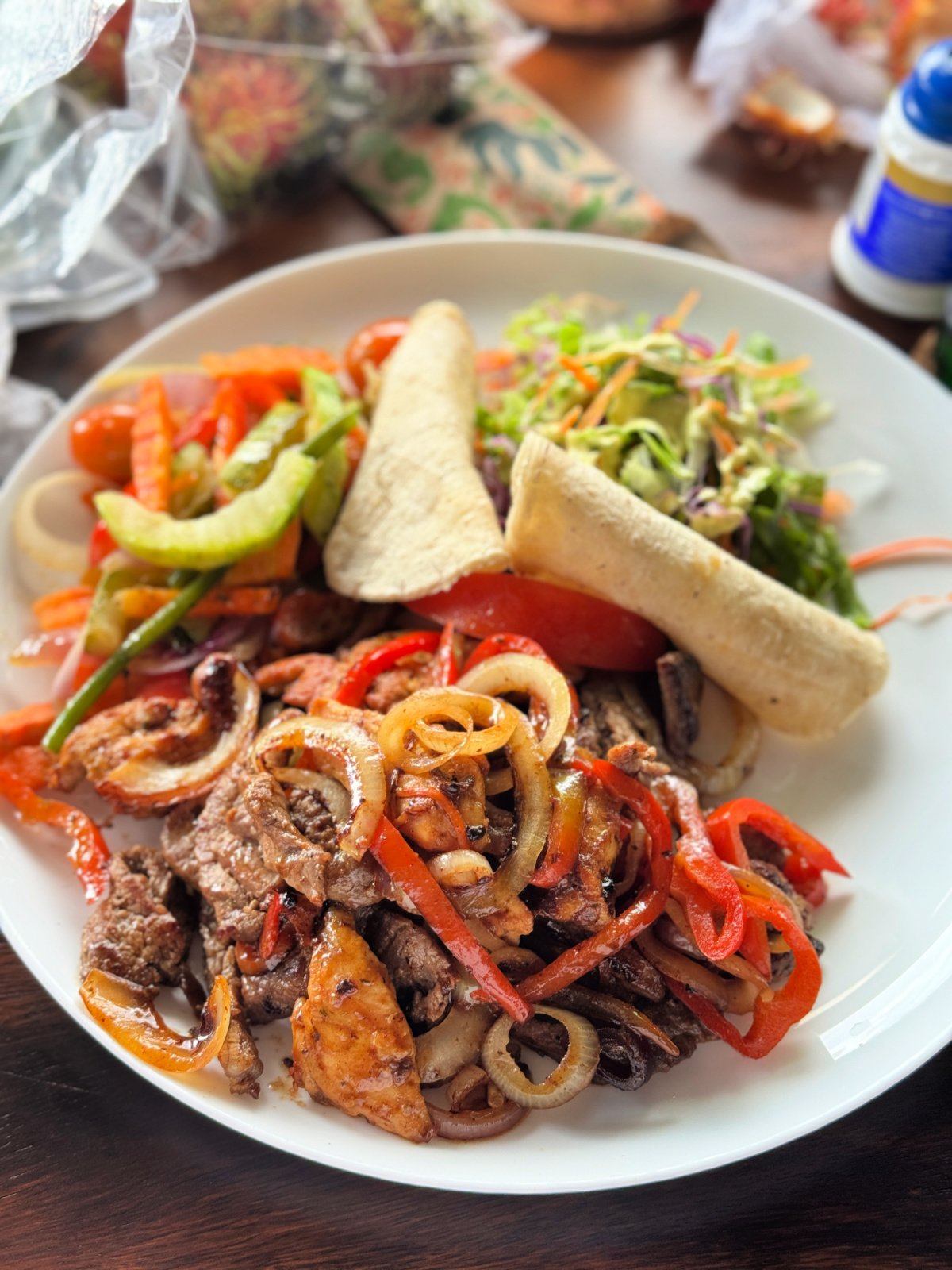 Plate of steak and chicken fajitas with grilled peppers and onions, tortillas, and fresh salad in Costa Rica.