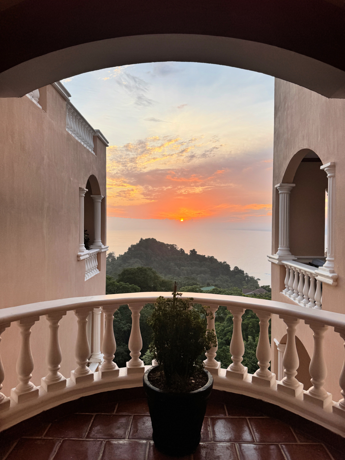 Sunset view over the Pacific Ocean from a balcony at Colonial Pacifico in Manuel Antonio, Costa Rica, framed by archways and white columns.