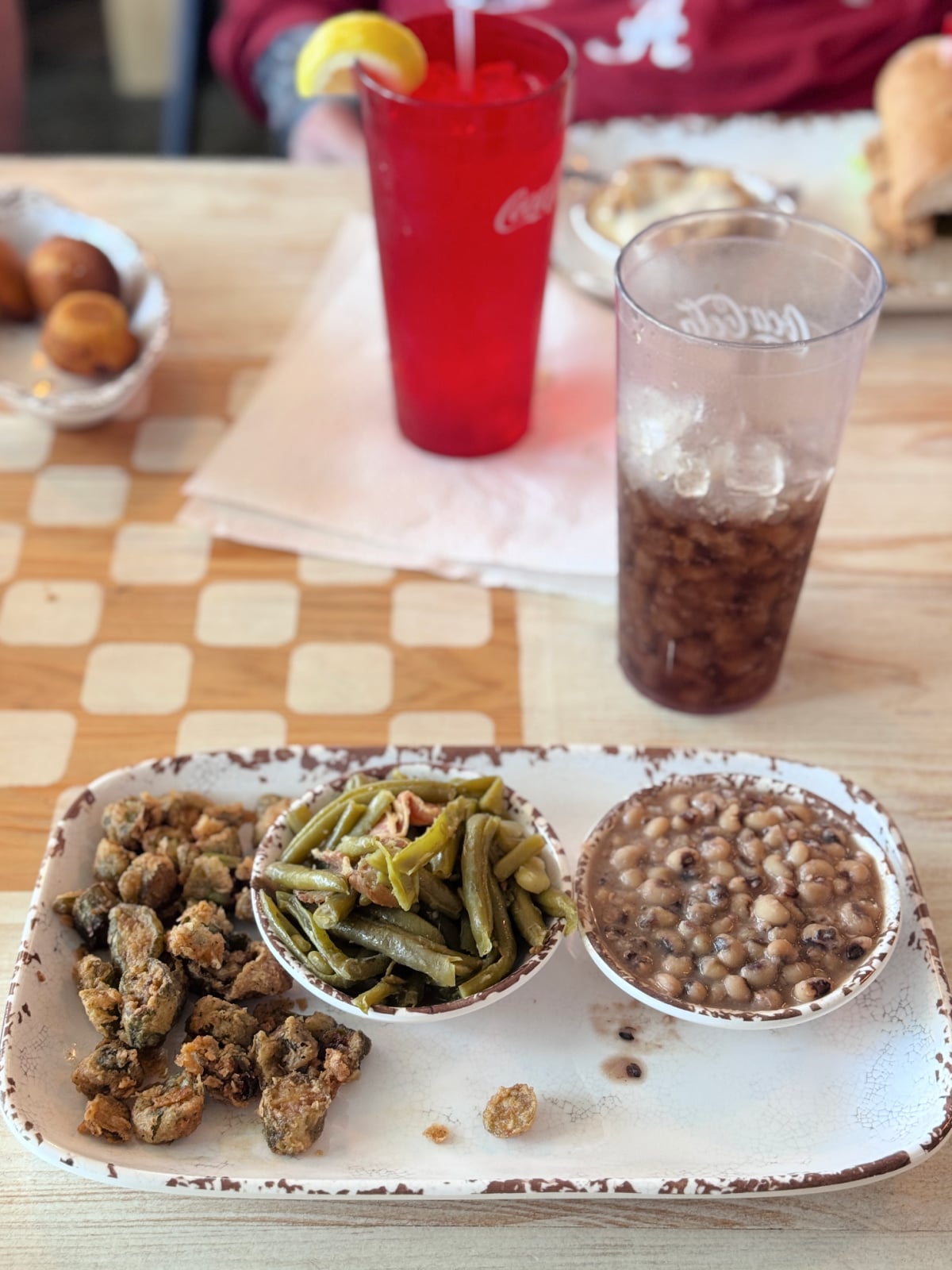 Southern lunch plate with fried okra, green beans, black-eyed peas, and sweet tea on a rustic tray.