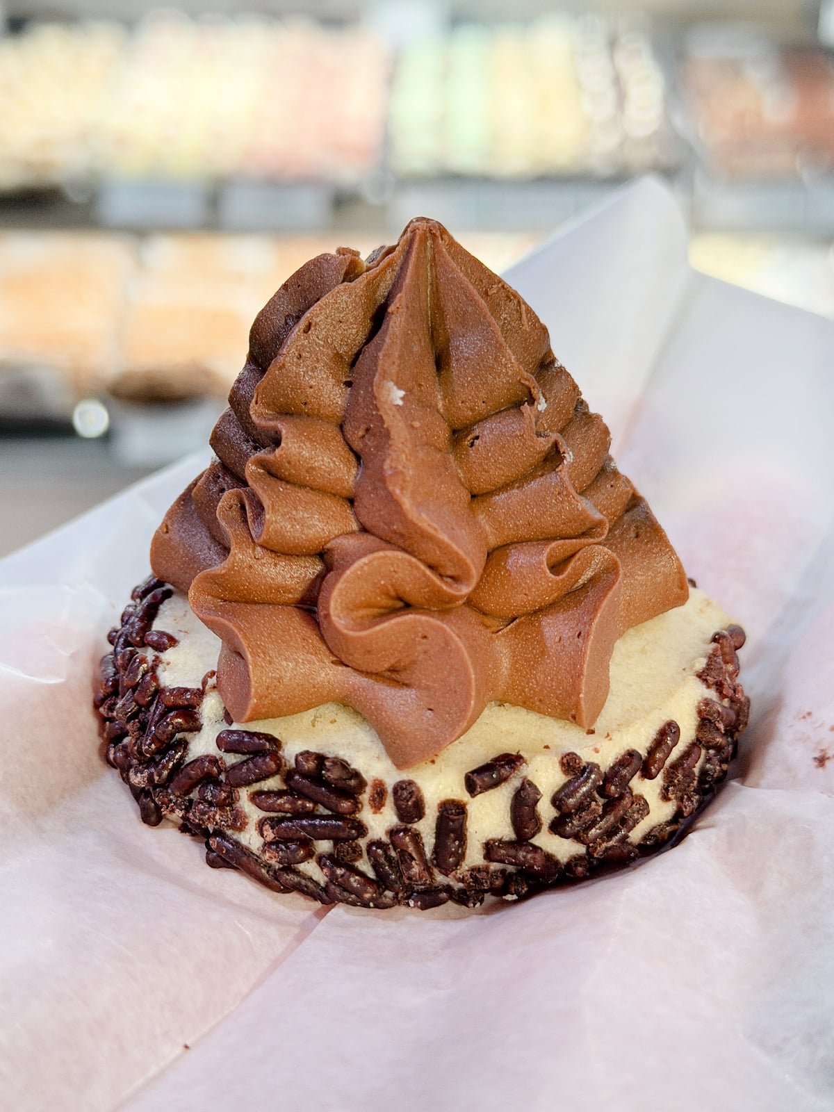 Chocolate cookie topped with swirled frosting and chocolate sprinkles.