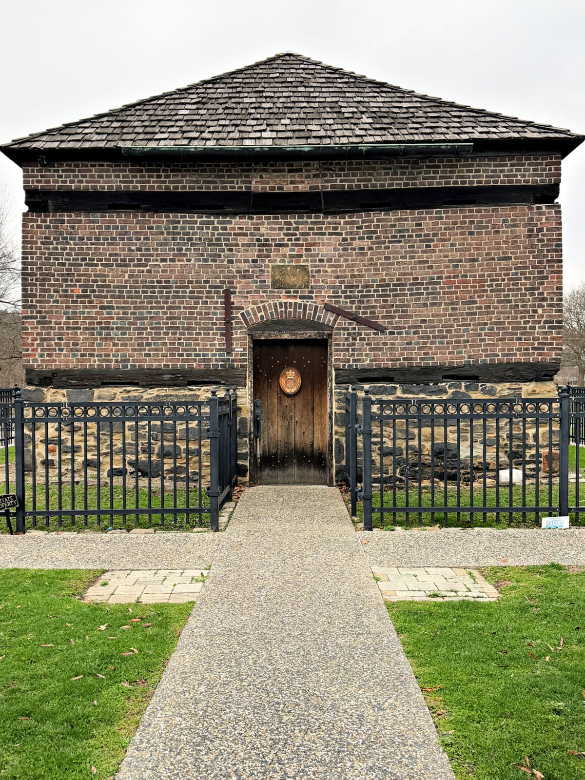 Fort Pitt blockhouse building in Pittsburgh with brick walls and a fenced walkway leading to the entrance.