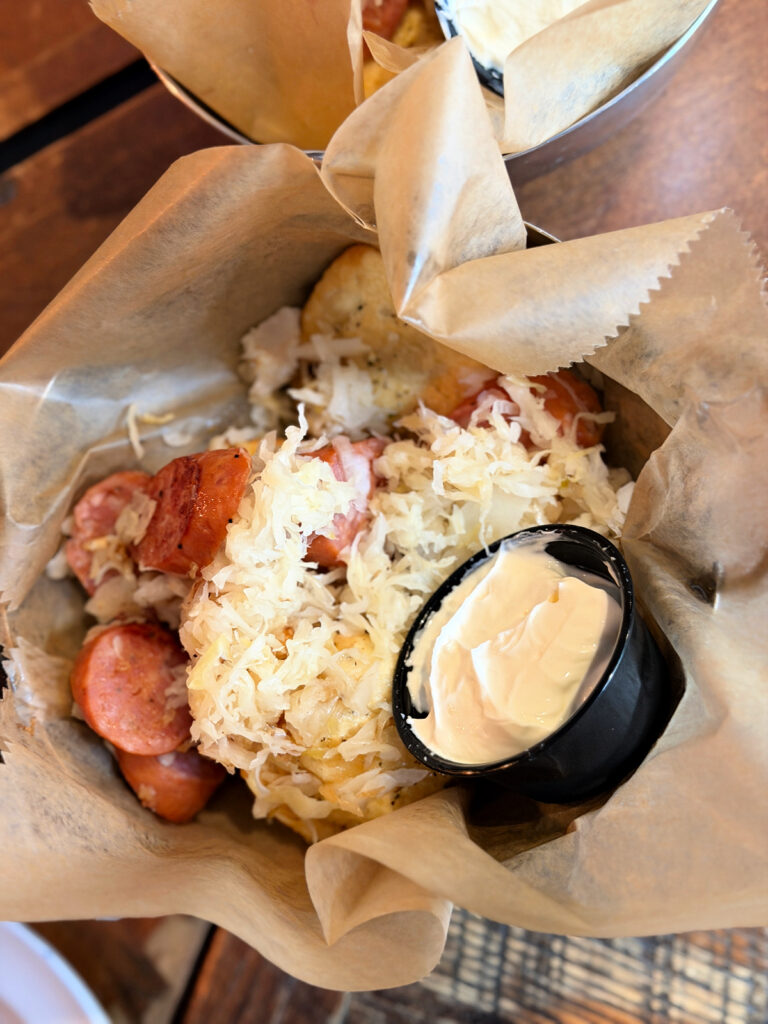 Pierogies with sausage and sauerkraut served in a basket with a side of sour cream.