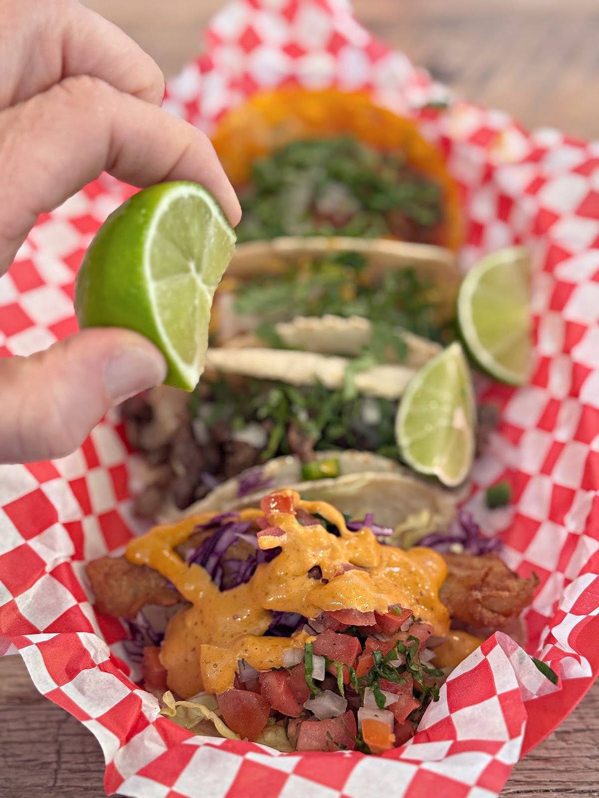 Lime being squeezed over tacos.