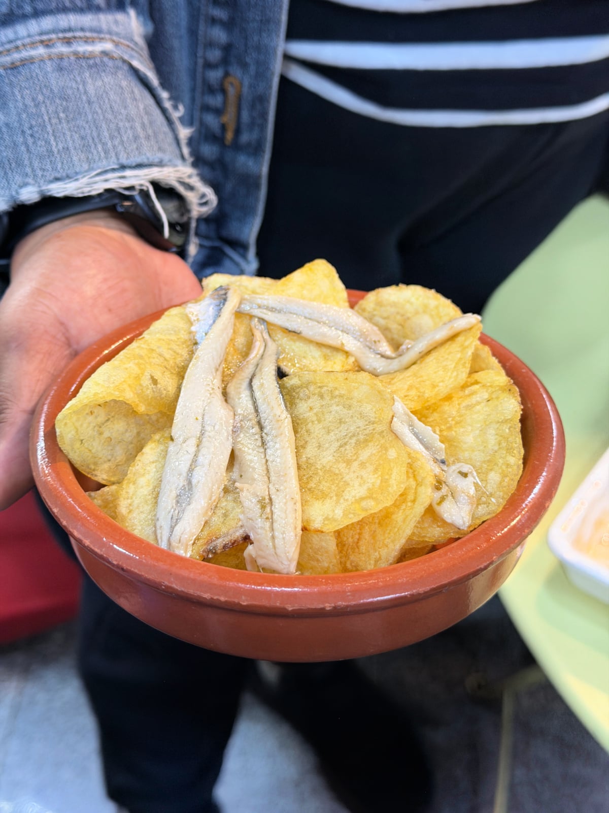 Bowl of crispy potato chips topped with marinated white anchovies served during a Madrid food tour.