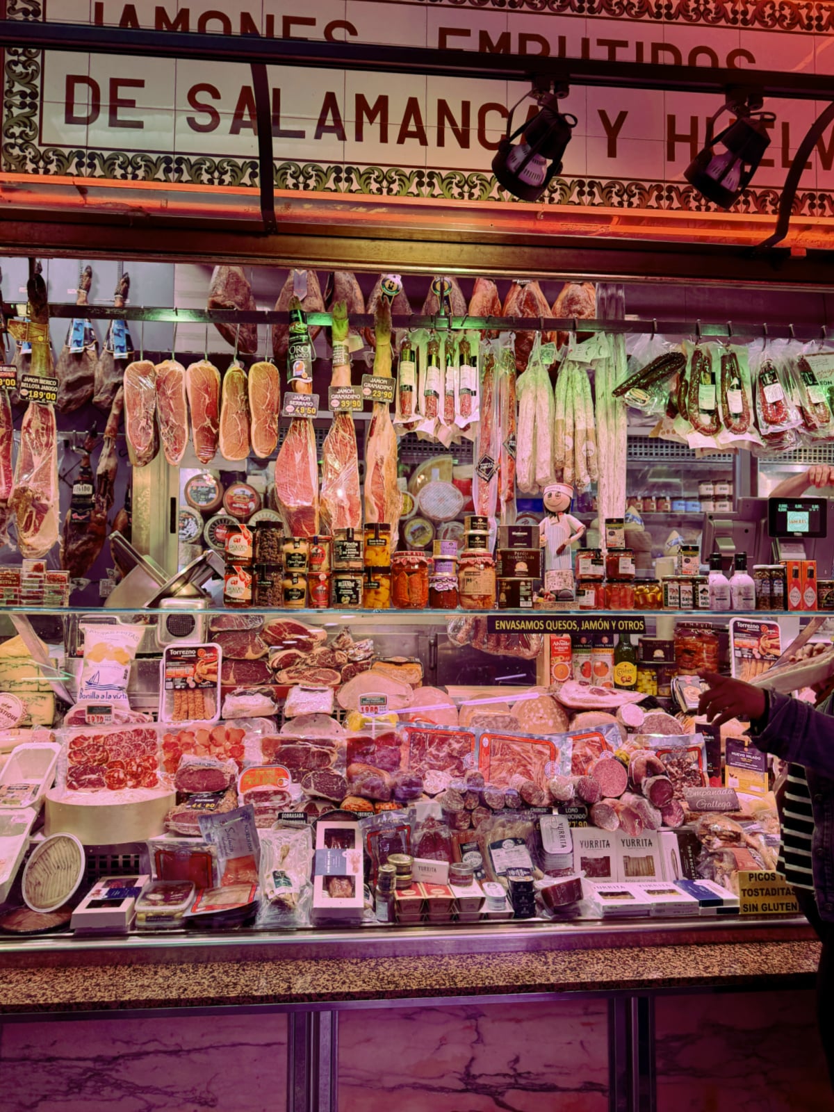 Traditional butcher shop in Madrid displaying hanging cured hams, sausages, cheeses, and Spanish meats.