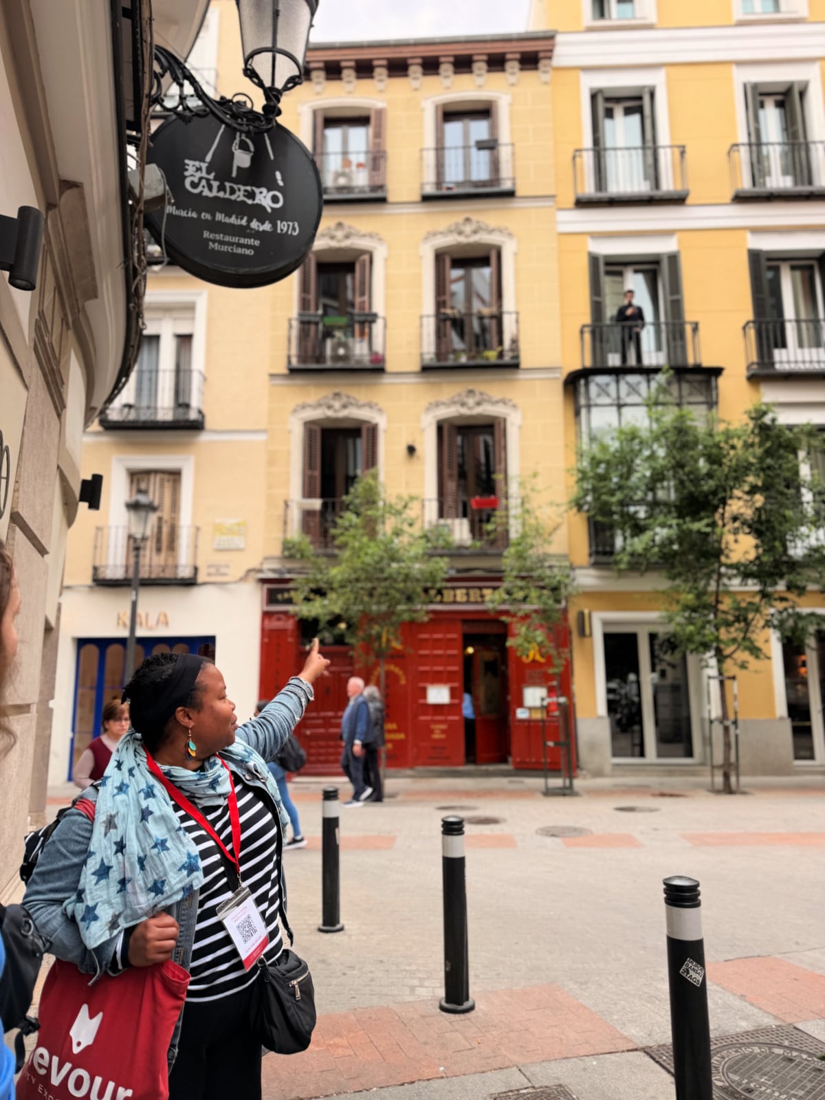 Food tour guide pointing toward a historic building connected to Cervantes in Madrid.