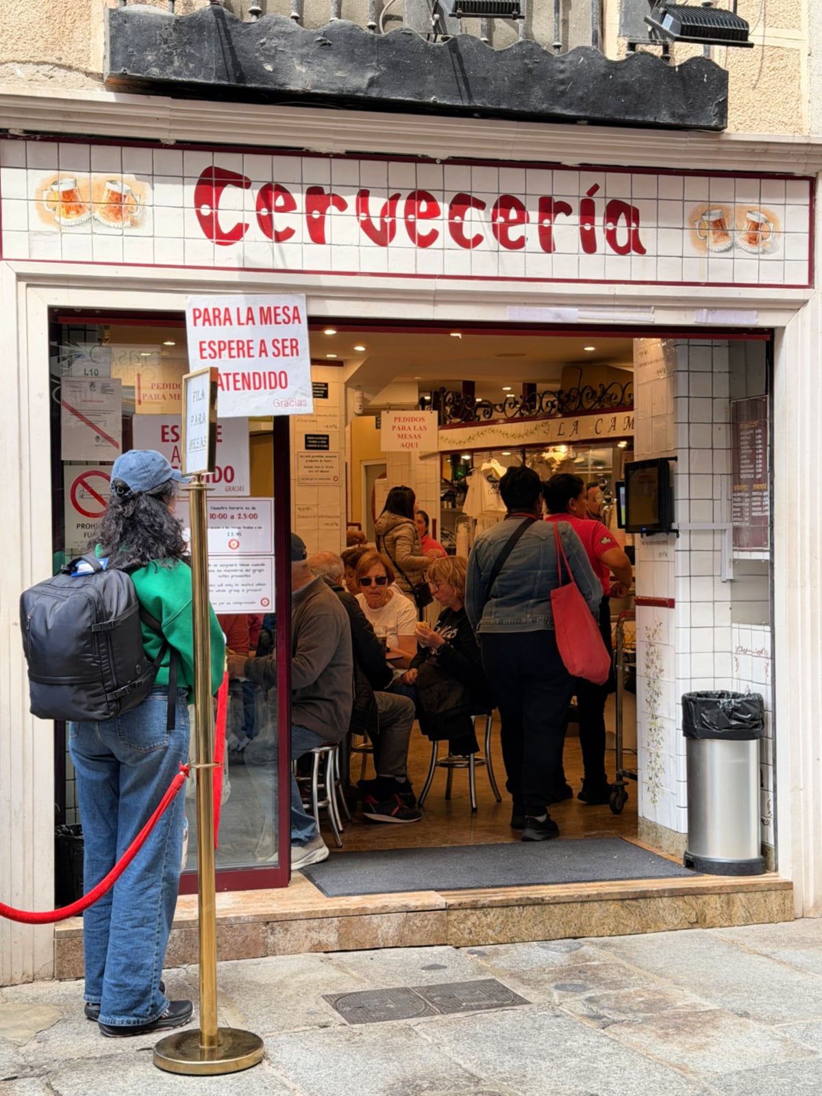 Busy cervecería entrance in Madrid filled with locals and visitors enjoying tapas and drinks.