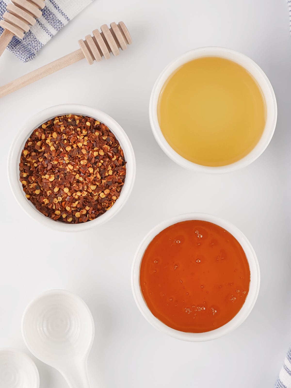 Ingredients for hot honey arranged on a white background, including honey, apple cider vinegar, and red pepper flakes.