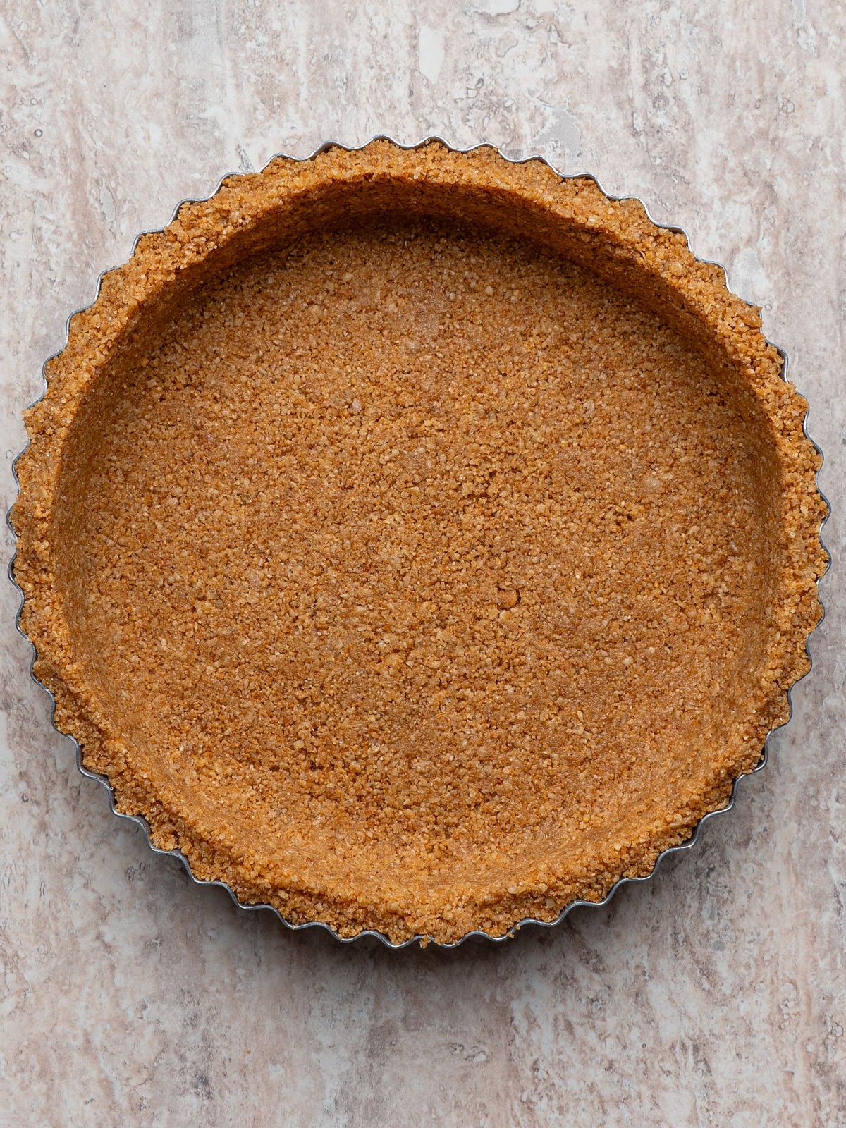 Baked graham cracker crust pressed into a fluted tart pan, ready to be filled.