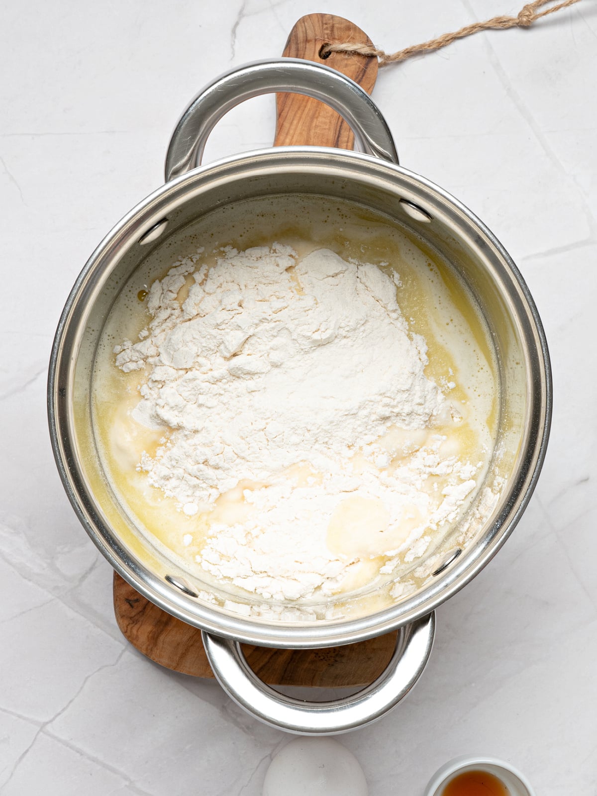 Flour added to the butter and water mixture in a saucepan during the first step of making churro dough.